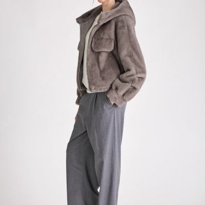 Mulher de casaco cinza felpudo e calças largas cinza com botas pretas em fundo branco