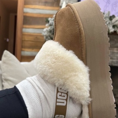 Pantufa UGG de plataforma castanha com pêlo branco e meia branca com texto UGG