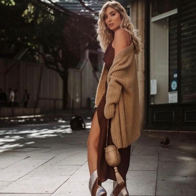 Mulher de vestido castanho, cardigan bege e sapatos prateados na rua