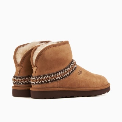 Botas baixas castanhas tipo UGG com interior forrado a pelo e faixa decorativa preta e branca.