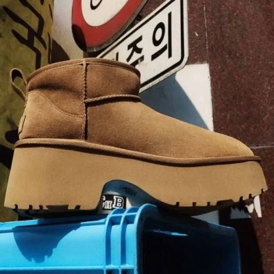Bota castanha clara com sola grossa sobre caixa azul em ambiente urbano