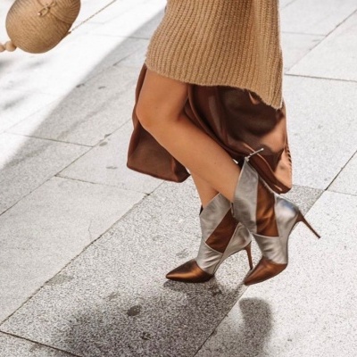 Botas de salto alto metálicas prateadas e bronze num pavimento urbano claro