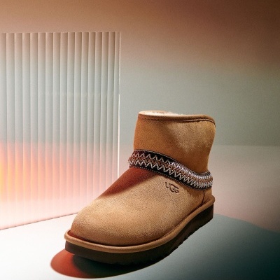 Bota UGG bege em camurça com detalhe em faixa zigzag colorida.