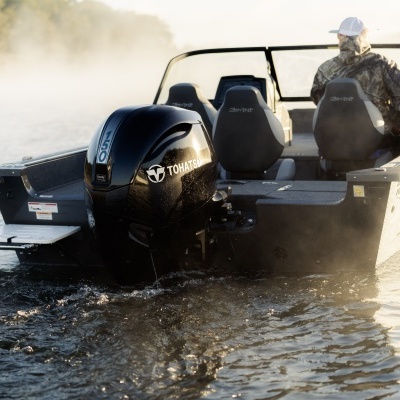 Barco de pesca com motor fora de bordo Tohatsu 150 preto em água com nevoeiro.