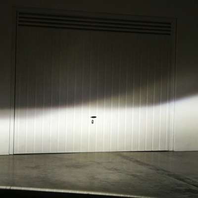 Porta de garagem branca com painéis verticais e fechadura central