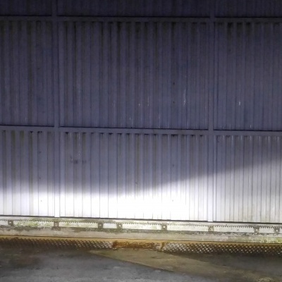 Porta metálica de enrolar cinza num ambiente exterior com chão de cimento