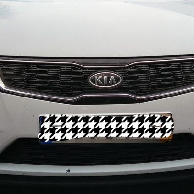 Frente de carro Kia branco com grelha preta e faróis ligados