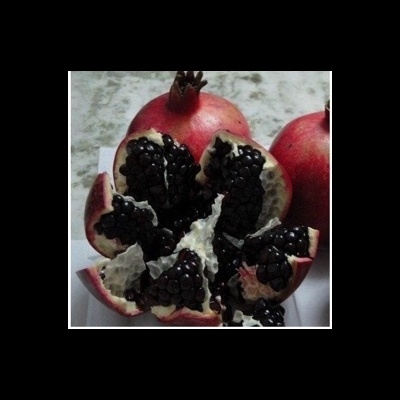 Romã aberta com sementes pretas brilhantes em superfície branca