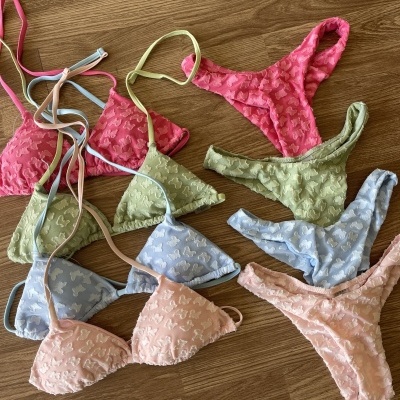 Conjunto de lingerie colorida com padrão de borboletas sobre chão de madeira.