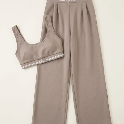 Conjunto de calças largas e soutien desportivo castanho claro com logótipo alo na faixa elástica.