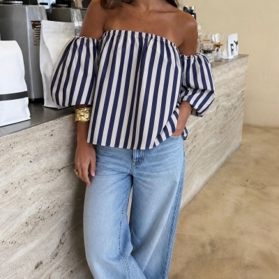 Blusa riscada azul e branca com decote ombro a ombro e mangas bufantes com jeans azul claro