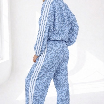 Mulher com conjunto desportivo azul claro com padrão de manchas e riscas brancas