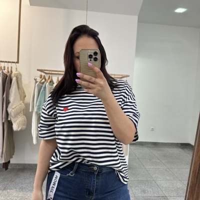 Mulher com t-shirt de riscas azuis e brancas com coração vermelho e jeans azuis numa loja de roupa