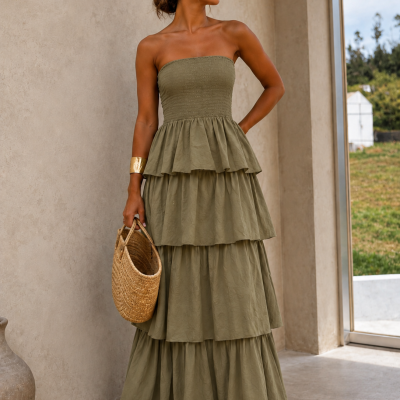 Mulher com vestido longo verde-oliva, pulseira dourada, bolsa de palha e óculos de sol