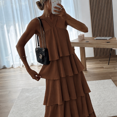 Vestido comprido castanho e mala preta em ambiente interior