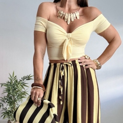 Conjunto feminino com top amarelo claro, calças largas às riscas amarelas e castanhas e mala às riscas