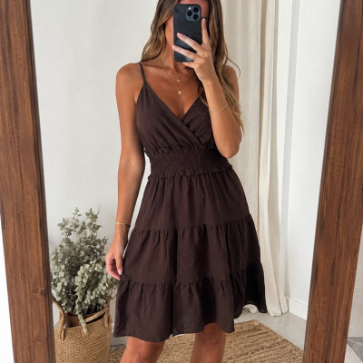 Vestido casual castanho escuro com alças finas e saia em camadas, vestido por mulher numa sala moderna