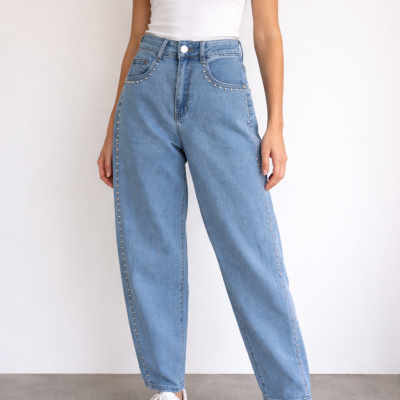 Calças de ganga azul claro com tachas prateadas lado a lado, top branco e sapatilhas brancas.