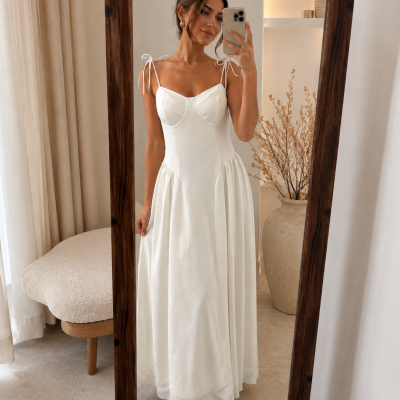 Vestido longo branco com alças finas e laços nos ombros visto em espelho