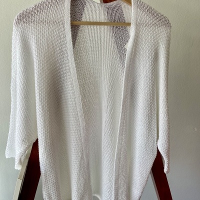 Casaco cardigan branco de malha pendurado em cabides de madeira