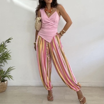 Mulher com top rosa e calças largas com riscas coloridas em ambiente interior minimalista
