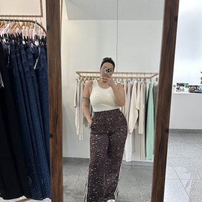 Pessoa com calças largas estampadas e top branco em frente a espelho de madeira