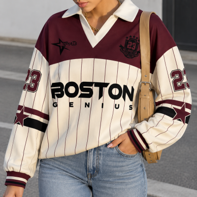 Mulher com sweatshirt creme às riscas vermelhas e detalhes grenás, com texto preto, a usar jeans azuis claros.