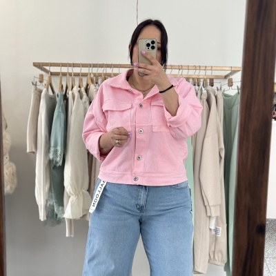 Pessoa com casaco rosa claro e jeans azul claro tira selfie numa loja