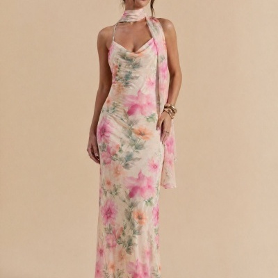 Vestido longo floral rosa com echarpe correspondente, usado por mulher em fundo bege