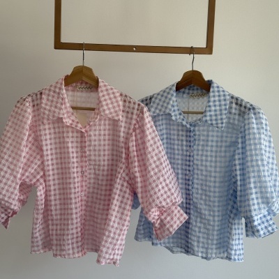 Duas camisas xadrez rosa e azul em cabides de madeira