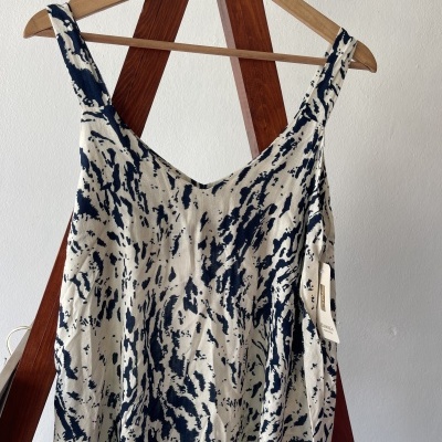 Blusa feminina sem mangas azul e branca pendurada num cabide de madeira