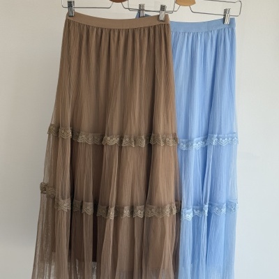 Duas saias midi plissadas, castanha e azul clara, com rendas, penduradas em cabides