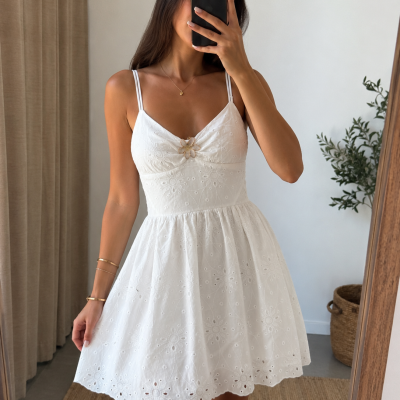 Vestido branco com alças finas, bordado floral e detalhe de flor dourada no peito.