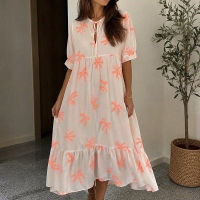 Vestido midi branco com padrões laranja e manga curta usado por mulher em interior