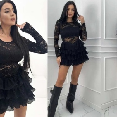 Vestido preto curto com renda e folhos usado por mulher com botas pretas em ambiente branco