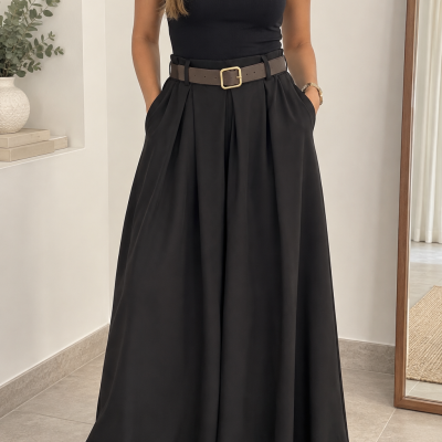 Mulher com blusa preta sem mangas, saia preta larga, cinto castanho, sapatos brancos e pulseira dourada