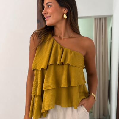 Mulher a usar blusa amarela mostarda de um ombro só com camadas franzidas e calças bege largas