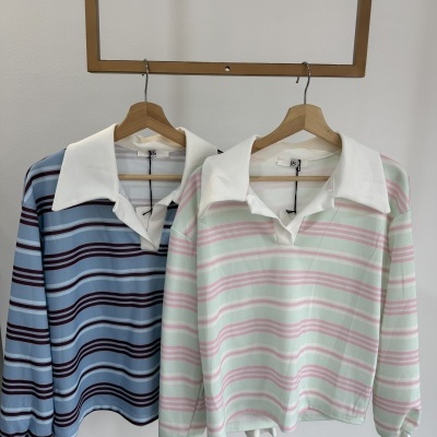 Dois polos de riscas pendurados em cabides de madeira