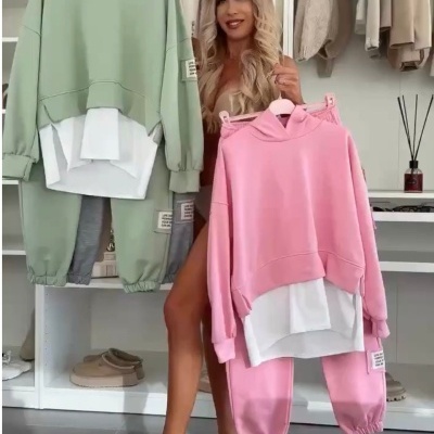 Conjuntos de roupa com capuz e calças em verde-claro e rosa com detalhe branco, apresentados por mulher em closet