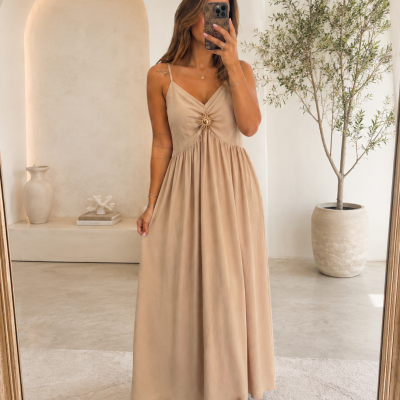 Vestido comprido bege claro com detalhe decorativo redondo no peito, alças finas, em ambiente minimalista claro