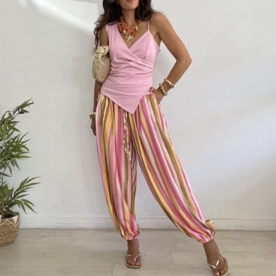 Mulher com roupa rosa e calças às riscas coloridas em ambiente interior