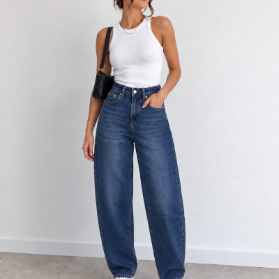 Mulher com top branco e jeans largos azuis em fundo branco