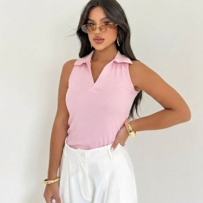 Mulher com blusa rosa e calças brancas com óculos e acessórios dourados.