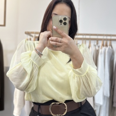 Blusa amarela clara com mangas bufantes e cinto castanho com fivela dourada