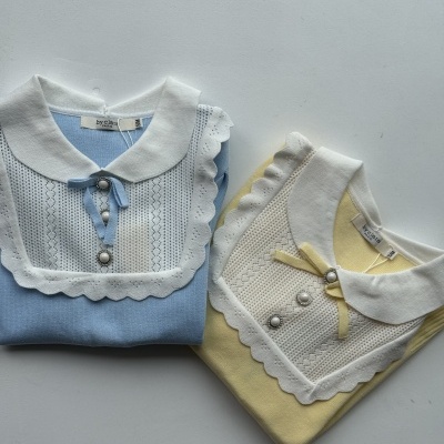 Duas camisolas dobradas com golas brancas e detalhes de renda e botões pérola.
