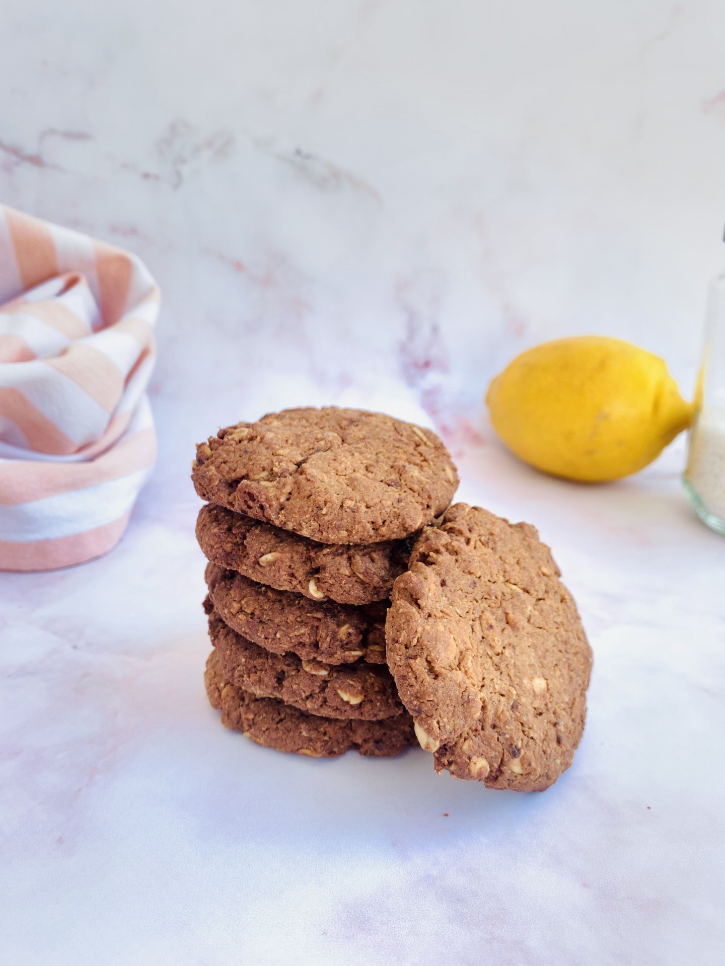 cookies de limão BIO sem glúten - 9 unidades, 160g Bolachas castanhas empilhadas sobre a mesa com limão e pano listrado ao fundo