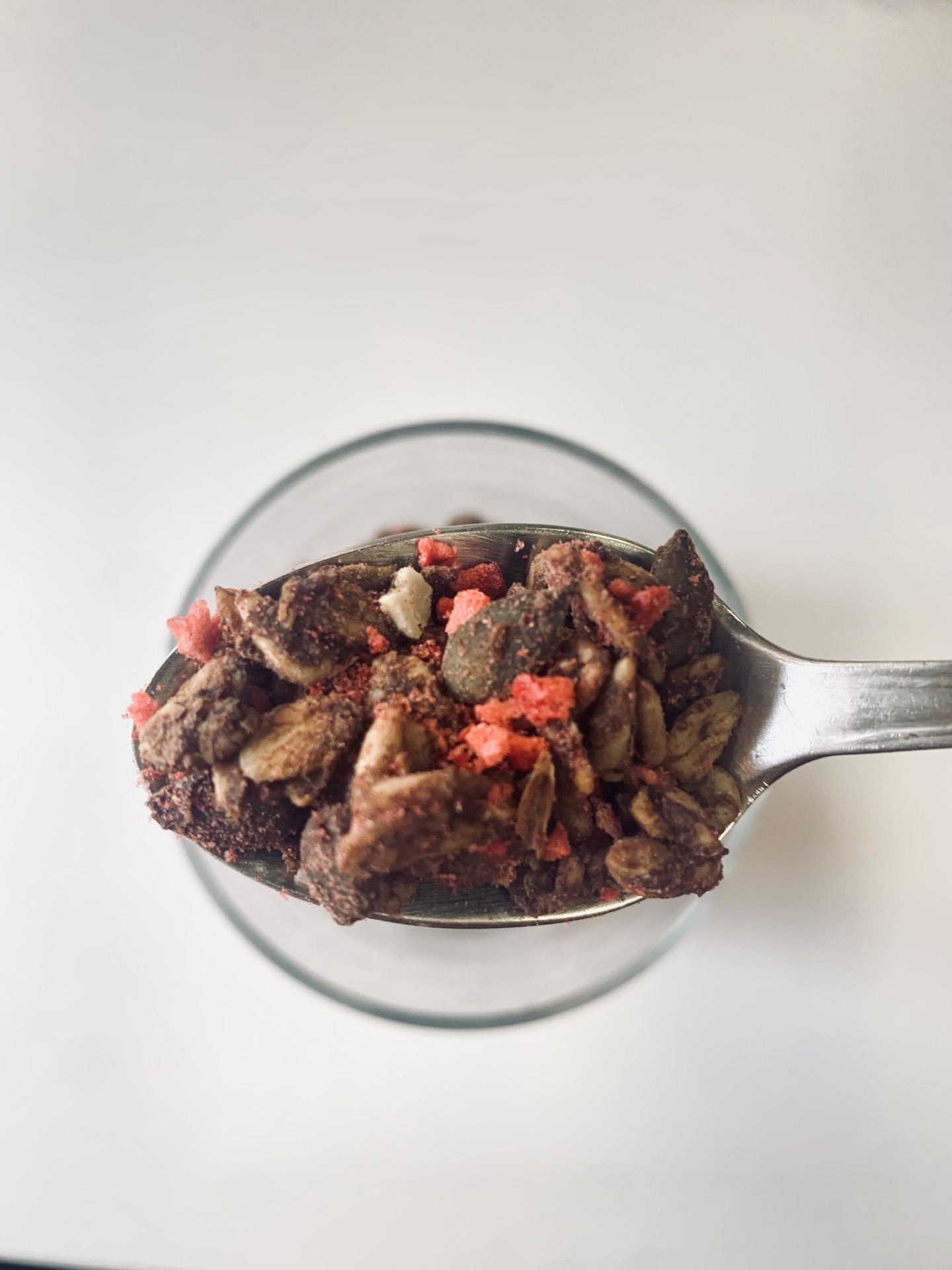 Granola de alfarroba e morango, naturalmente isenta de glúten, baixa em açúcares - 400g Colher com granola mista colorida em fundo branco