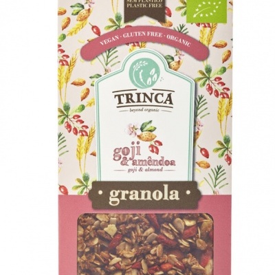 Embalagem colorida de granola Trinca com goji e amêndoa, janela transparente mostrando o conteúdo, texto e selos orgânicos.