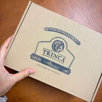 Caixa de cartão castanha da marca TRINCA sobre mesa de madeira