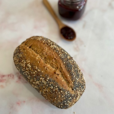 Pão integral com sementes, frasco e colher com compota vermelha